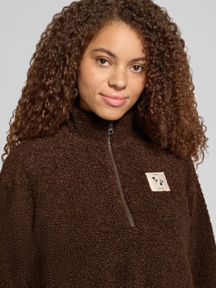 Frauenmodel trägt Troyer mit Teddyfleece-Struktur von PIECES in Braun, unifarben, Label Patch, strukturierte Oberfläche, Nahaufnahme Oberkörper.