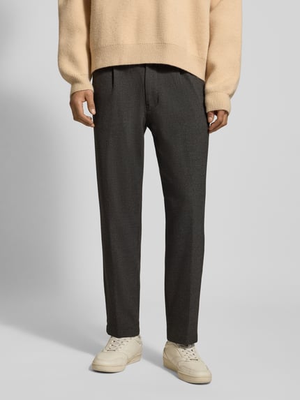 Männermodel trägt Tapered Bundfaltenhose mit Viskose-Anteil von Marc O'Polo Denim in Melange-Optik, seitliche Eingrifftaschen, Ganzkörperansicht von vorne.