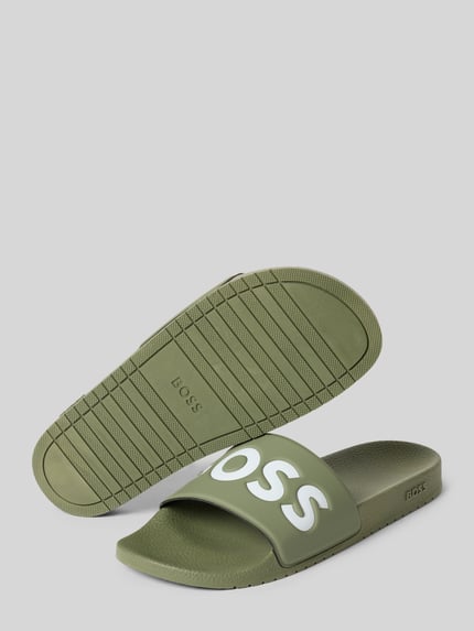 Produktfoto, Badeschuhe mit Logo Print von BOSS in Grün mit Two-Tone-Optik, flacher Absatzform, europäische Herstellung, strukturierte Oberfläche