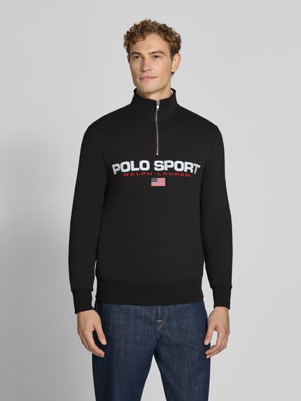 Männermodel trägt Relaxed Fit Troyer aus Baumwoll-Mix von Polo Ralph Lauren in Schwarz mit Logo-Print, Ganzkörperansicht von vorne.
