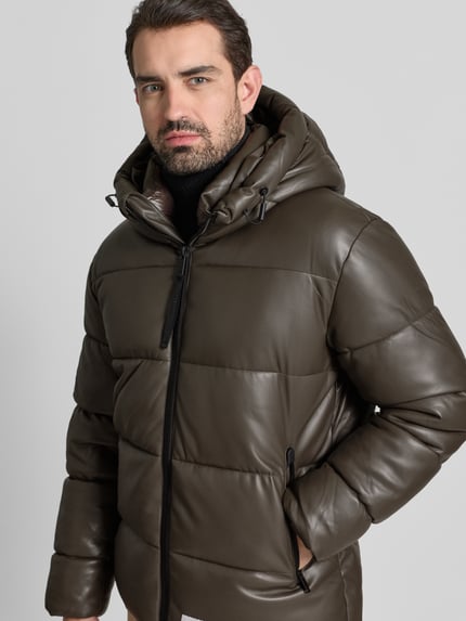 Männermodel trägt Regular Fit Steppjacke mit Logo-Patch Modell 'Coen' von khujo in Oliv, Stepp-Optik, Ganzkörperansicht von vorne.
