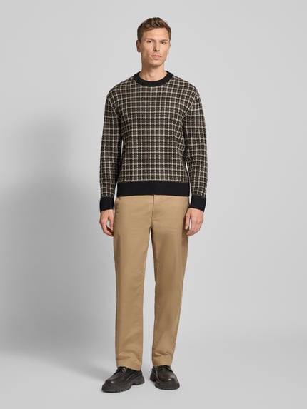 Männermodel trägt Regular Fit Strickpullover aus Woll-Mix Modell 'MIKOLAS' von SELECTED HOMME, kariert, Crew Neck, Ganzkörperansicht von vorne.
