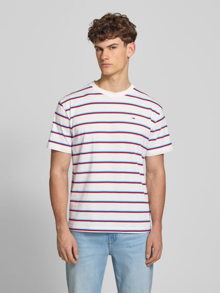 Männermodel trägt Regular Fit T-shirt uit puur katoen van Tommy Jeans met all-over motief, gestreept patroon, logostitching, jersey. Ganzkörperansicht van voren.