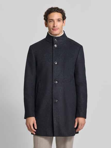 Männermodel trägt Wollmantel Modell 'MAICO' mit Stehkragen von JOOP!, unifarben mit Struktur, seitliche Eingrifftaschen, Ganzkörperansicht von vorne.