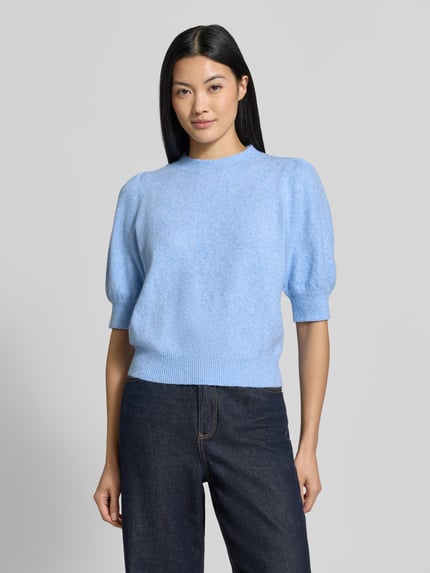 Frauenmodel trägt Regular Fit Pullover mit Puffärmeln von VERO MODA in Hellblau zu dunkler Jeans, weiche Textur, Ganzkörperansicht von vorne.