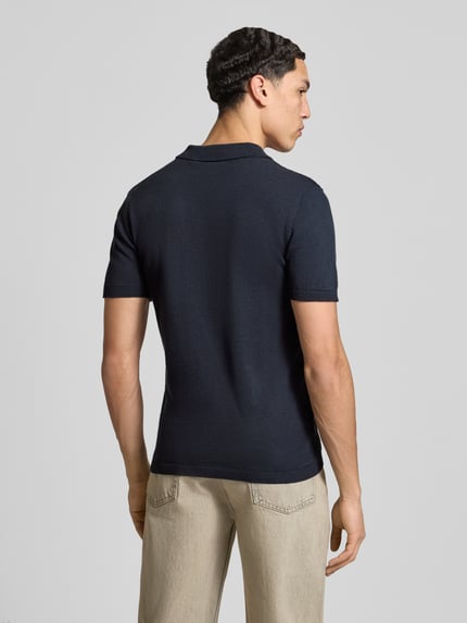 Männermodel trägt Slim Fit Poloshirt in Strick-Optik Modell 'Baron' von Blend, dunkelblau, reine Baumwolle, Ganzkörperansicht Rückansicht.