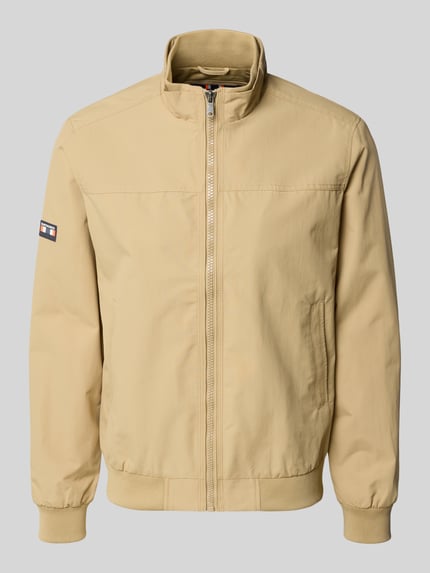 Produktfoto, kurtka 'Jacke mit Stehkragen und Eingrifftaschen' od Superdry, beżowa, krój regular fit, stójka, zamek błyskawiczny, wpuszczane kieszenie, długość tyłu w rozmiarze M: 70 cm, szerokość ramion w rozmiarze M: 44 cm, szerokość klatki piersiowej w rozmiarze M: 41 cm, długość rękawów w rozmiarze M: 68 cm