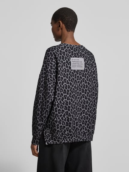 Frauenmodel trägt Oversized Strickpullover im Allover-Look von Smith and Soul, grau-schwarzes Leopardenmuster, Baumwoll-Mix, Ganzkörperansicht Rückansicht.