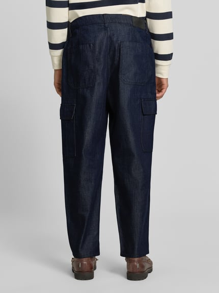 Männermodel trägt dunkelblaue Tapered Fit Jeans aus Baumwoll-Lyocell-Mix Modell 'Isak' von Marc O'Polo DENIM, lockere Passform, Ganzkörperansicht Rückansicht.