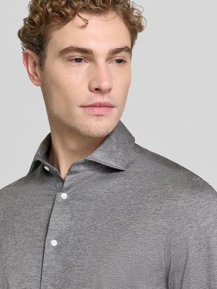 Männermodel trägt Slim Fit Businesshemd aus Baumwoll-Modal-Mix Modell 'Light Spread Kent' von Seidensticker in Grau mit feiner Struktur, Knopfleiste und Haifischkragen, Nahaufnahme Oberkörper.