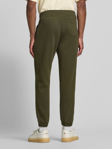 Männermodel trägt Relaxed Fit Sweathose aus Baumwoll-Mix von Polo Ralph Lauren in Olivgrün mit glatter Struktur, Ganzkörperansicht Rückansicht. Herren Sweathose von Polo Ralph Lauren