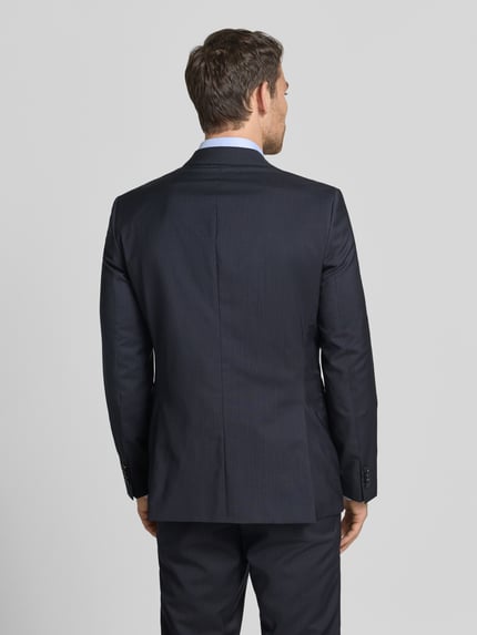 Männermodel trägt Slim Fit Anzugsakko aus reiner Schurwolle Modell 'H-HUGE-263' von BOSS, dunkelblau, Nadelstreifen-Muster, Ganzkörperansicht Rückansicht.