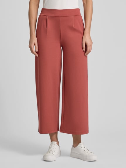 Frauenmodel trägt Wide Fit Stoffhose mit Viskose-Anteil Modell 'Kate' von ICHI in Rot mit Bundfalten und Gesäßtasche, Nahaufnahme Oberkörper