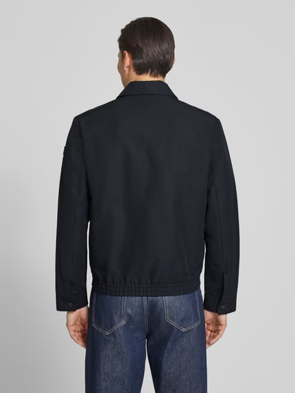 Männermodel trägt Regular Fit Blouson mit elastischem Bund von Marc O'Polo, look: effen, regular fit pasvorm, platte kraag, ritssluiting, labelpatch, lange mouw met drukknoop, elastische rompzoom, zij-steekzakken, binnenzak, kleur donkerblauw, textuur glad, ganzkörperansicht rückansicht.