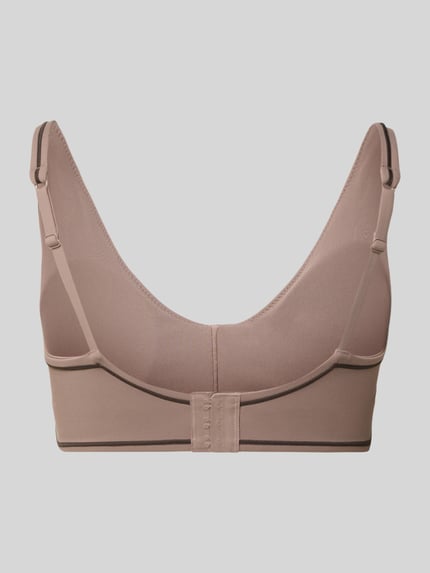 Frauenmodel trägt Slim Fit Sport BH mit Logo-Detail Modell 'PURELUXE' von Fabletics in Beige mit Hakenverschluss, Ganzkörperansicht Rückansicht.