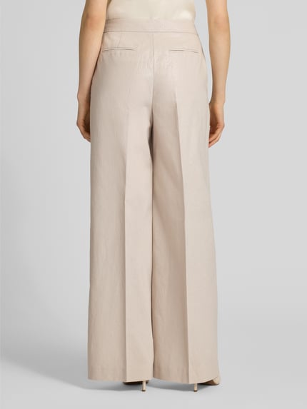 Modelka nosi Leinenhose mit Bügelfalte und Eingrifftaschen von Christian Berg Cocktail, len z dodatkiem bawełny, krój loose fit, sztruksowa tekstura, jasny beż, szerokie nogawki, zapięcie na haftkę i suwak, francuskie kieszenie, tylne kieszenie z lamówką, szerokość w rozmiarze 36: 39 cm, długość wewnętrzna nogawki: 82 cm, widok całej sylwetki z tyłu