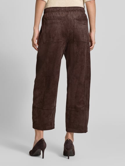 Frauenmodel trägt Loose Fit Kunstlederhose mit elastischem Bund Modell 'Tilda' von MAC in Braun mit sichtbarer Struktur, Ganzkörperansicht Rückansicht, Damen Leder- / Kunstlederhose von MAC.