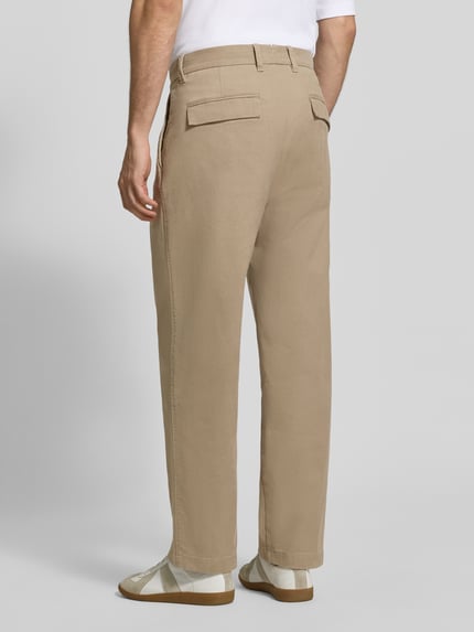 Männermodel trägt Weite Hose aus Baumwoll-Mix Modell 'Mossbo' von Marc O'Polo in Beige, glatte Struktur, Herren Weite Hose, Ganzkörperansicht Rückansicht.