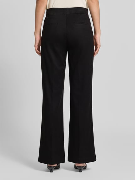 Frauenmodel trägt Boocut Fit Stoffhose mit Viskose-Anteil von Christian Berg Woman in Schwarz, glatte Textur, Paspeltaschen, Ganzkörperansicht Rückansicht.