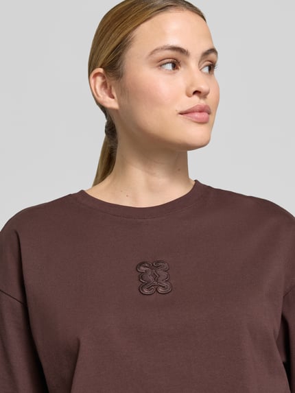 Vrouwenmodel draagt Cropped Boxy Fit T-shirt met ronde hals van Smith and Soul in puur katoen, stitching detail, kleur bruin, nahaufnahme bovenlichaam.