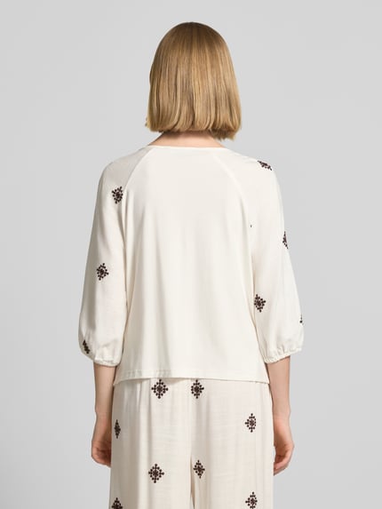 Frauenmodel trägt Bluse aus Viskose-Mix mit 3/4-Arm von Christian Berg Woman Selection in Creme mit dezentem Muster, Ganzkörperansicht Rückansicht.