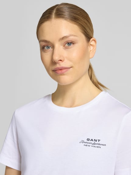 Frauenmodel trägt T-Shirt mit Label-Print und Rundhalsausschnitt von Gant, Reine Baumwolle, Regular-Fit, Damen T-Shirt, Nahaufnahme Oberkörper.