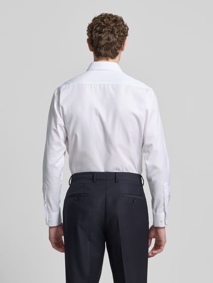 Männermodel trägt Regular Fit Businesshemd aus Uni Solid von Eterna, reine Baumwolle, weiß, Kentkragen, Sportmanschetten, Ganzkörperansicht Rückansicht.