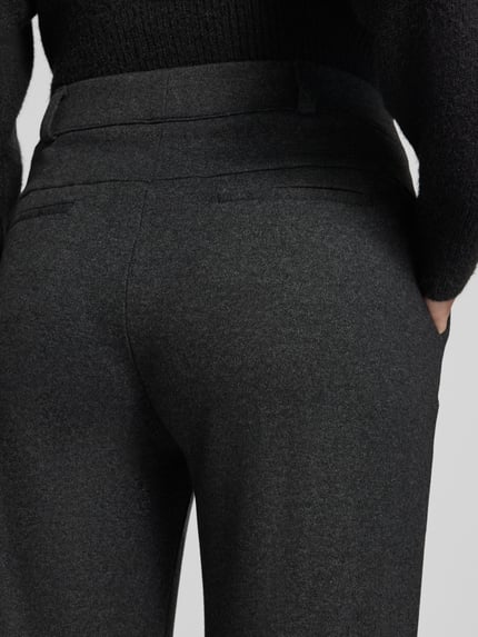 Frauenmodel trägt Regular Fit Weite Hose mit Bügelfalten von BRAX in Dunkelgrau, strukturierte Webware mit Gesäßtaschen, Nahaufnahme Rückansicht.
