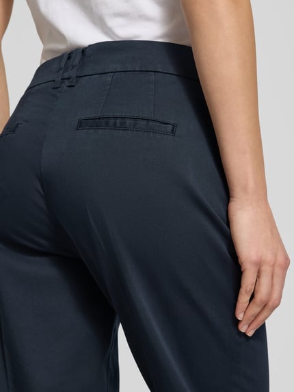 Frauenmodel trägt Straight Fit Stoffhose mit Lyocell-Anteil Modell 'Mara' von Brax in Dunkelblau, glatte Textur, Detailaufnahme Rückansicht.