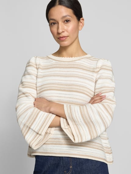 Frauenmodel trägt gestreiften, creme-weiß und beige Pullover mit strukturierter Textur, Nahaufnahme Oberkörper.