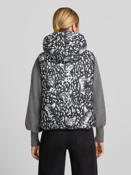 Frauenmodel trägt Regular Fit Weste mit Wendefunktion von Marc Cain in Schwarz mit weißem Animal-Print, strukturierte Oberfläche, Ganzkörperansicht Rückansicht. Damen Weste von Marc Cain.