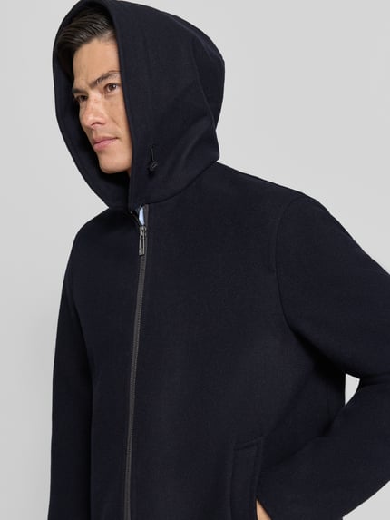 Männermodel trägt Regular Fit Jacke aus Schurwoll-Mix von Armani Exchange in Dunkelblau mit Kapuze und Reißverschluss, Nahaufnahme Oberkörper. Kontext: Herren Jacke, Schurwoll-Mix, Regular Fit, Kapuze mit Tunnelzug, Zweiwege-Reißverschluss, Eingrifftaschen, Maße bei Größe M: Rückenlänge 74 cm, Schulterbreite 50 cm, Brustweite 61 cm, Ärmellänge 66 cm.