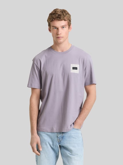 Mannenmodel draagt Relaxed Fit T-Shirt aus reiner Baumwolle van Tom Tailor Denim, uni, labelprint, ronde hals, korte mouw, puur katoen. Ganzkörperansicht van voren.