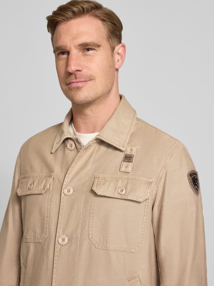 Männermodel trägt Regular Fit Hemdjacke mit Brusttaschen Modell 'Goodale' van Blauer Usa in beige katoen, detailopname bovenlichaam.