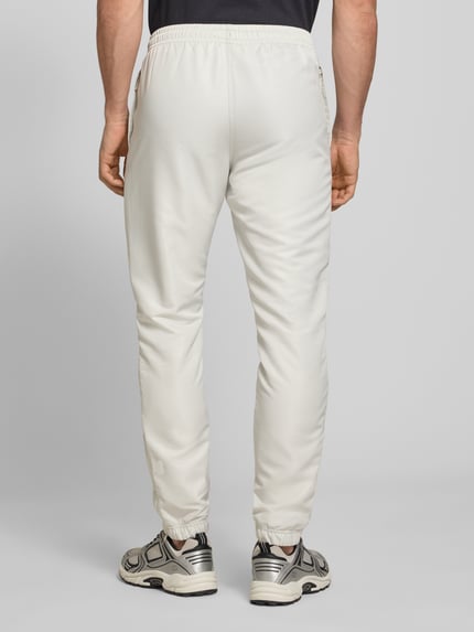 Männermodel trägt Regular Fit Tracksuit mit Logo-Stitching Modell 'Carson' von SERGIO TACCHINI in Weiß, elastische Abschlüsse, Ganzkörperansicht Rückansicht.