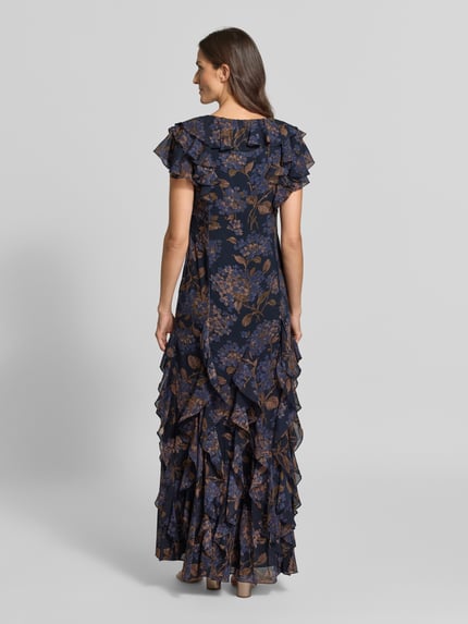Frauenmodel trägt Eng anliegendes Abendkleid mit Rüschen von Lauren Ralph Lauren in Dunkelblau mit floralem Muster, Ganzkörperansicht Rückansicht. Damen Abendkleid von Lauren Ralph Lauren.