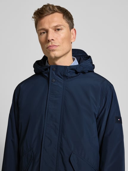 Männermodel trägt Regular Fit Funktionsjacke mit Kapuze von Tommy Hilfiger, Optik: Unifarben, Nahaufnahme Oberkörper.