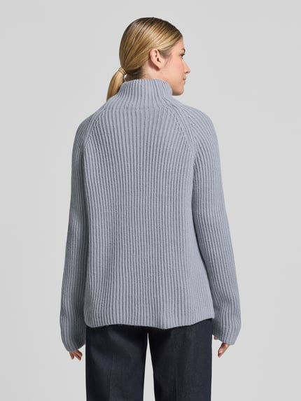 Vrouwenmodel draagt Strickpullover mit Stehkragen Modell 'ARWEN' van DRYKORN, katoenmix, regular fit, grofgebreid, grijs, detailopname rugaanzicht.