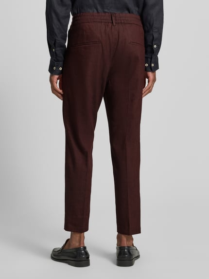 Männermodel trägt Hose aus Leinen-Mix mit Gesäßtaschen von Drykorn, Slim-Fit, elastischer Bund, Ganzkörperansicht Rückansicht.