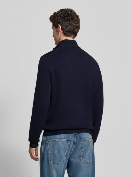 Männermodel trägt Pullover mit Logo-Patch Troyer von LACOSTE in unifarbener Strickoptik, Regular Fit, Hochkragen, Rückansicht.