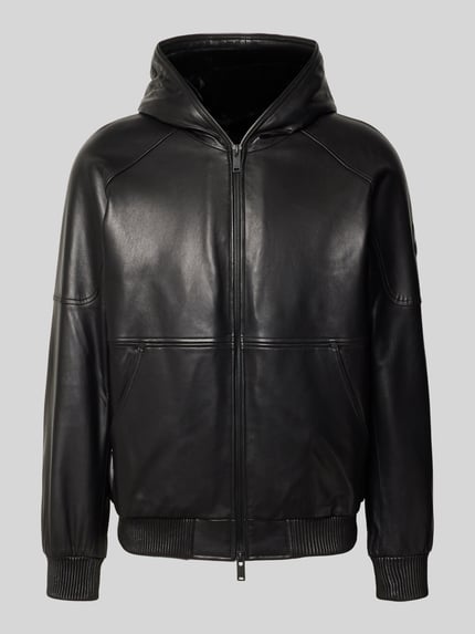 Produktfoto, Jacke in Leder-Optik von Moose Knuckles, czarny materiał skóropodobny, zamek błyskawiczny dwustronny, kieszeń kangurka, prążkowane wykończenia, luźny krój, długość tyłu w rozmiarze M 69 cm, szerokość ramion w rozmiarze M 43 cm, długość rękawów w rozmiarze M 67 cm