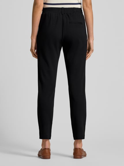Frauenmodel trägt Easy Pants mit Bundfalten von TOM TAILOR in Schwarz, Viskosemischung mit Stretch-Anteil, Ganzkörperansicht Rückansicht.