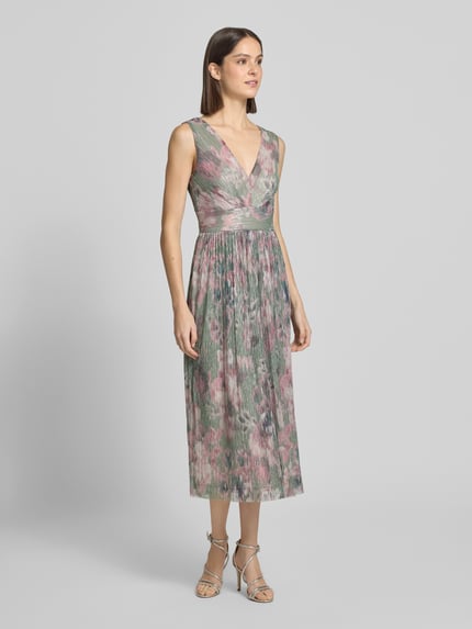Modelka kobieca nosi Cocktailkleid mit V-Ausschnitt od Swing, wzór crinkle, długość midi, kolorowe tonacje, widok całej sylwetki z przodu.