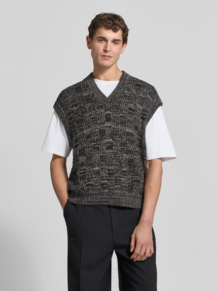 Männermodel trägt Regular Fit Pullunder aus Baumwolle von Filippa K mit V-Ausschnitt, Strukturmuster und gerippten Abschlüssen, Ganzkörperansicht von vorne.