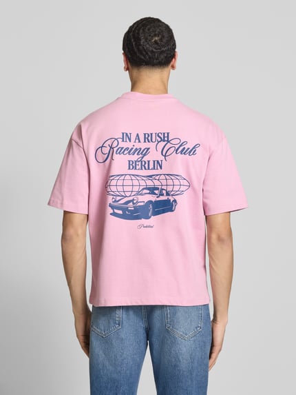Männermodel trägt Regular Fit T-Shirt aus reiner Baumwolle Modell 'IN A RUSH' von PROHIBITED in Rosa mit blauem Print, Ganzkörperansicht Rückansicht.