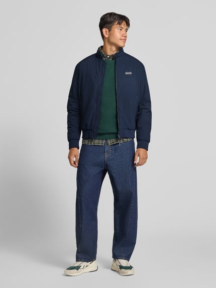 Männermodel trägt donkerblauwe bomberjack met opstaande kraag van JACK & JONES, Logo, ritssluiting, regular fit, model 'BROOKLYN', heren, Ruglengte maat M 67 cm, schouderbreedte 49 cm, borstwijdte 59 cm, mouwlengte 66 cm, Ganzkörperansicht von vorne.