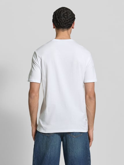 Männermodel trägt T-Shirt mit Label-Patch Modell 'BADGE' im 2er-Pack von Calvin Klein Jeans, weiße Baumwolle, gerader Schnitt, Ganzkörperansicht Rückansicht.