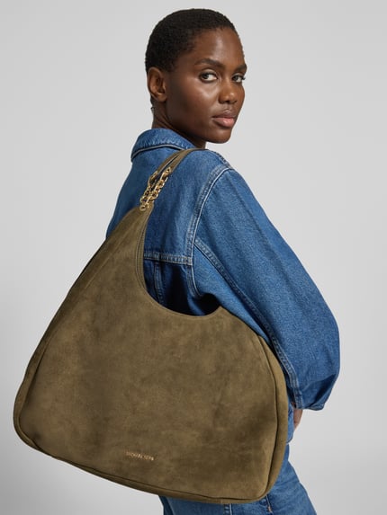 Kobiece modelka nosi torebkę z prawdziwej skóry model 'ELLIE' od MICHAEL Michael Kors w kolorze oliwkowym, faktura gładka, na ramieniu, szerokość w rozmiarze 1: 42 cm, długość w rozmiarze 1: 41 cm, głębokość w rozmiarze 1: 14 cm, długość paska na ramię w rozmiarze 1: 36 cm, zbliżenie na górną część ciała.