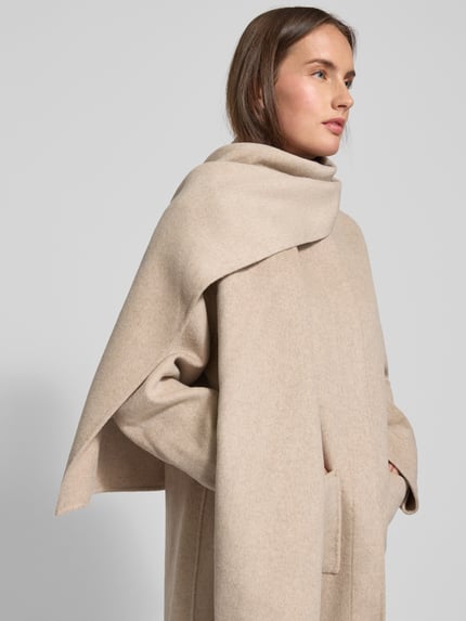 Modelka kobieca nosi Jacke mit Eingrifftaschen od Smith and Soul w kolorze beżowym, luźny krój, stójka, mieszanka wełny i lyocellu, z zaszytymi guzikami i kieszeniami, zdjęcie z przodu zbliżenie na górną część ciała.