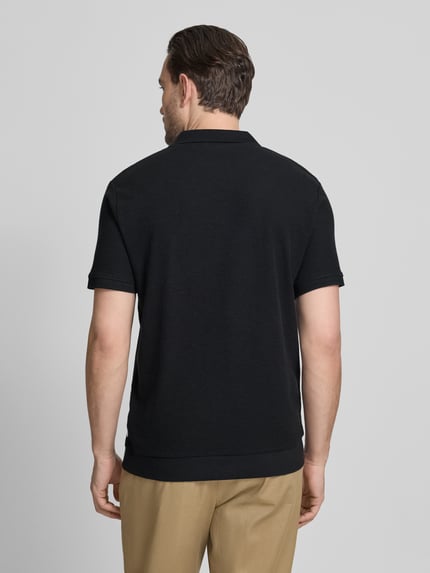 Męski model nosi Comfort Fit Poloshirt mit V-Ausschnitt von Lindbergh z bawełny, fakturowany wzór, detal z logo, długość tyłu 68 cm, Ganzkörperansicht Rückansicht.